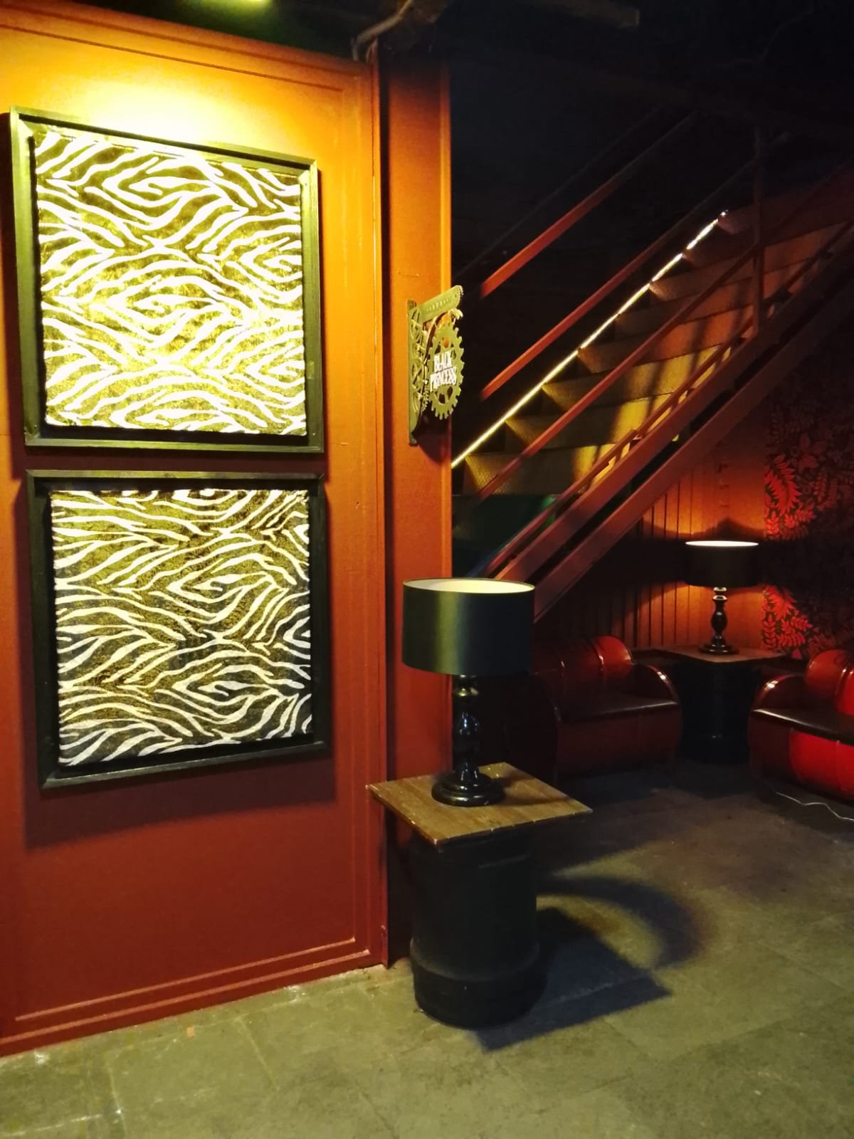 Térreo: quadros, escada iluminada e sofás de tambor